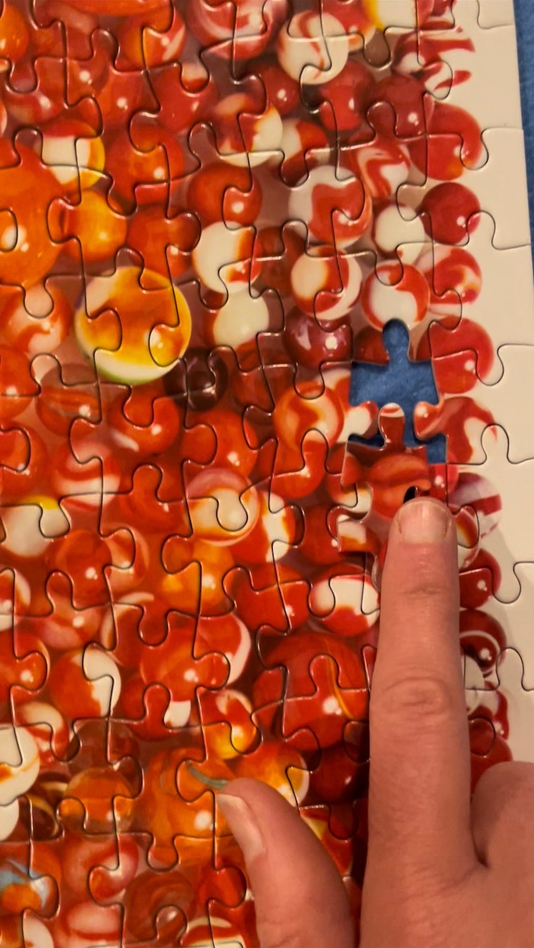 Putting in the last piece on a puzzle of red marbles
