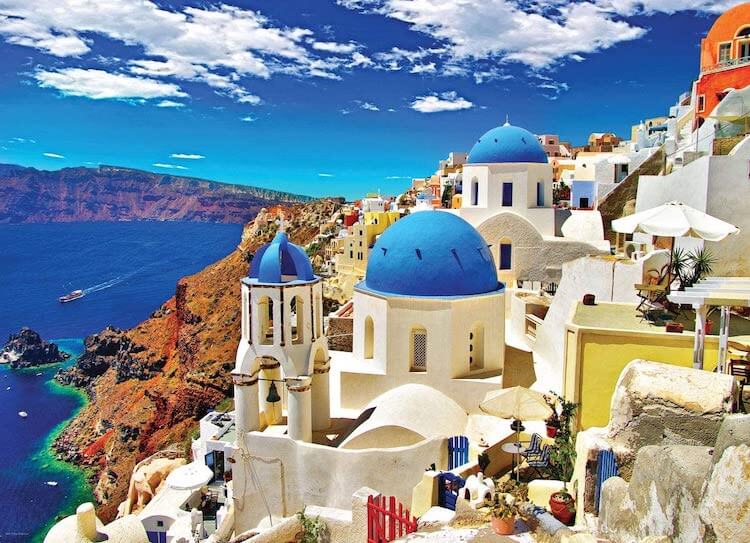 White buildings with blue roofs in Greece overlooking the blue sea with a blue sky with white clouds 