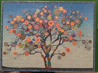 Puzzle image with blue background and tree with different colored manadalas on the branches