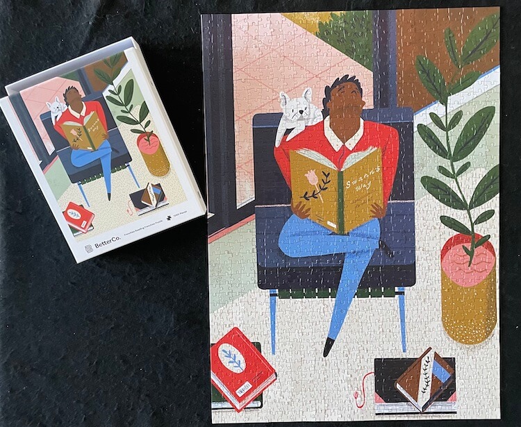 Puzzle of a man on a chair reading a book with a french bulldog on his shoulder and the puzzle box beside the puzzle
