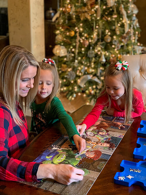 Mother and children puzzling in front of Christmas tree